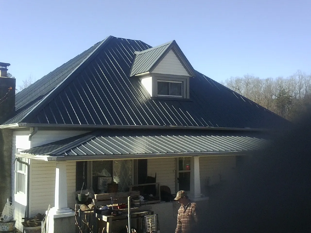 Dark blue standing seam metal roof with a dormer above a front porch in Blount