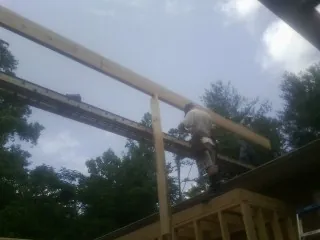 Carpenter setting a ridge beam over a new addition frame — Ice Dam Removal by Roofing Brothers in Blount