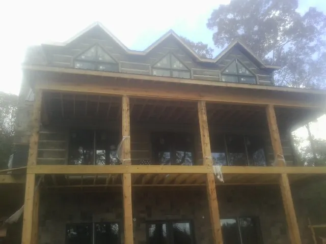 Dormers and porch framing on a large log home under construction — Roof Coating work by our crew in Blount