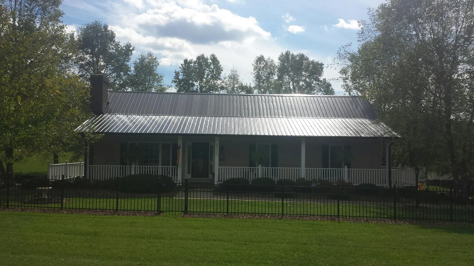 Gray metal roof on a brick ranch with a full width front porch — Gutter Guard Installation work by our crew in Blount