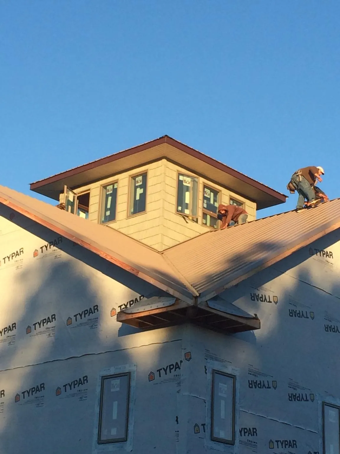 Roofers working around a rooftop cupola on a new metal roof at sunset — Roof Waterproofing in Blount by Roofing Brothers
